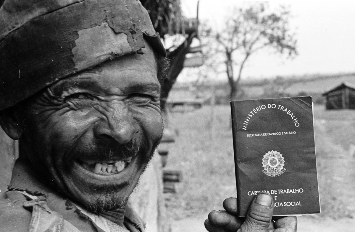 Trabalhador rural sorri exibindo carteira de trabalho