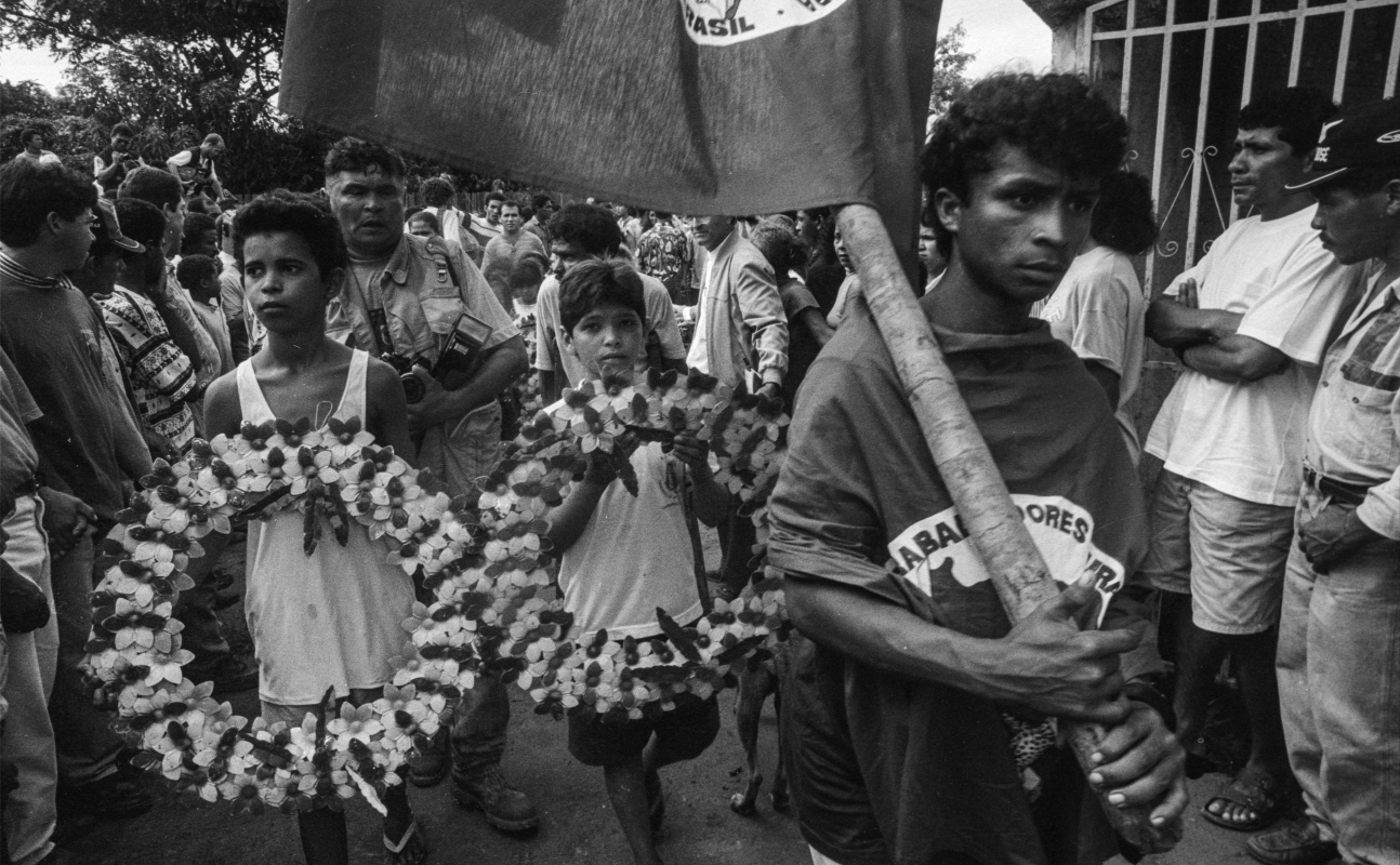 Familiares e militantes carregam a bandeira do MST e guirlandas de flores em uma longa caminhada até o local do enterro, em Curionópolis.