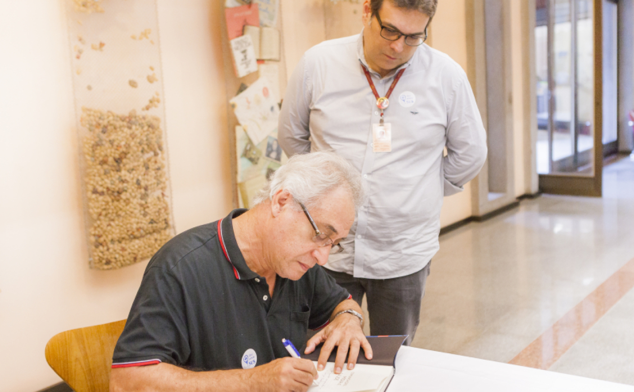 Umberto Trigueiros, ex-diretor do Icict, entregando o livro um dos organizadores do livro "Comunicação, Mídia e Saúde" - Foto: Raquel Portugal (Multimeios/Icict/Fiocruz)