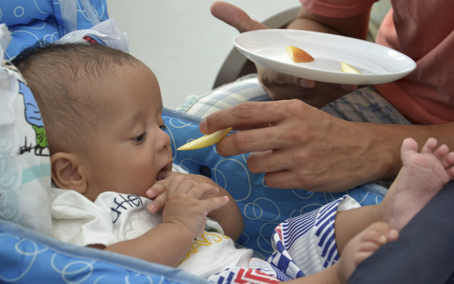 Foto de um bebê sendo alimentado pelo pai com uma fruta Foto: Salvador Scofano/Fiocruz Imagens.