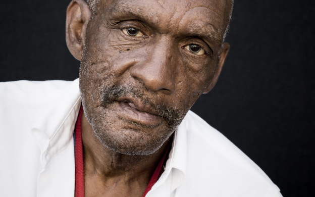Imagem de homem negro idoso, com camisa branca.