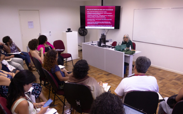 Foto de aula com alunos de costas e professora Inesita Araújo ao fundo. Foto: Raquel Portugal