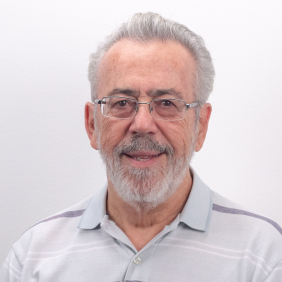 Pesquisador Luiz Otavio, homem branco, barba e cabelos grisalhos, camisa cinza listrada, fundo branco. Foto: Raquel Portugal/Multimeios.