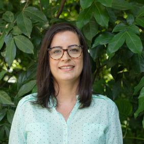 Pesquisadora Giseli Damacena, branca, mulher, cabelos castanhos lisos na altura do ombro, óculos e camisa verde.