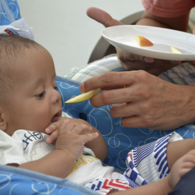 Foto de um bebê sendo alimentado pelo pai com uma fruta Foto: Salvador Scofano/Fiocruz Imagens.