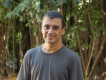 Pesquisador Paulo Borges, homem pardo, cabelos escuros, camisa cinza, com árvores ao fundo. Foto: Raquel Portugal/Multimeios.