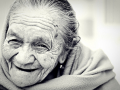 Foto do rosto de mulher idosa sorridente, em preto e branco