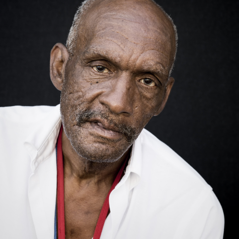 Imagem de homem negro idoso, com camisa branca.