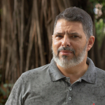 Pesquisador Wilson, branco, barba e cabelos grisalhos, camisa cinza