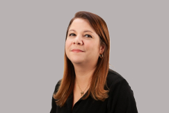 Pesquisadora Roberta Raupp, cabelos lisos vermelhos depois do ombro, com camisa preta, batom e brinco.