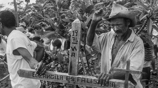 Trabalhador rural apóia mão sobre uma antiga lápide durante o sepultamento dos 19 companheiros assassinados no massacre
