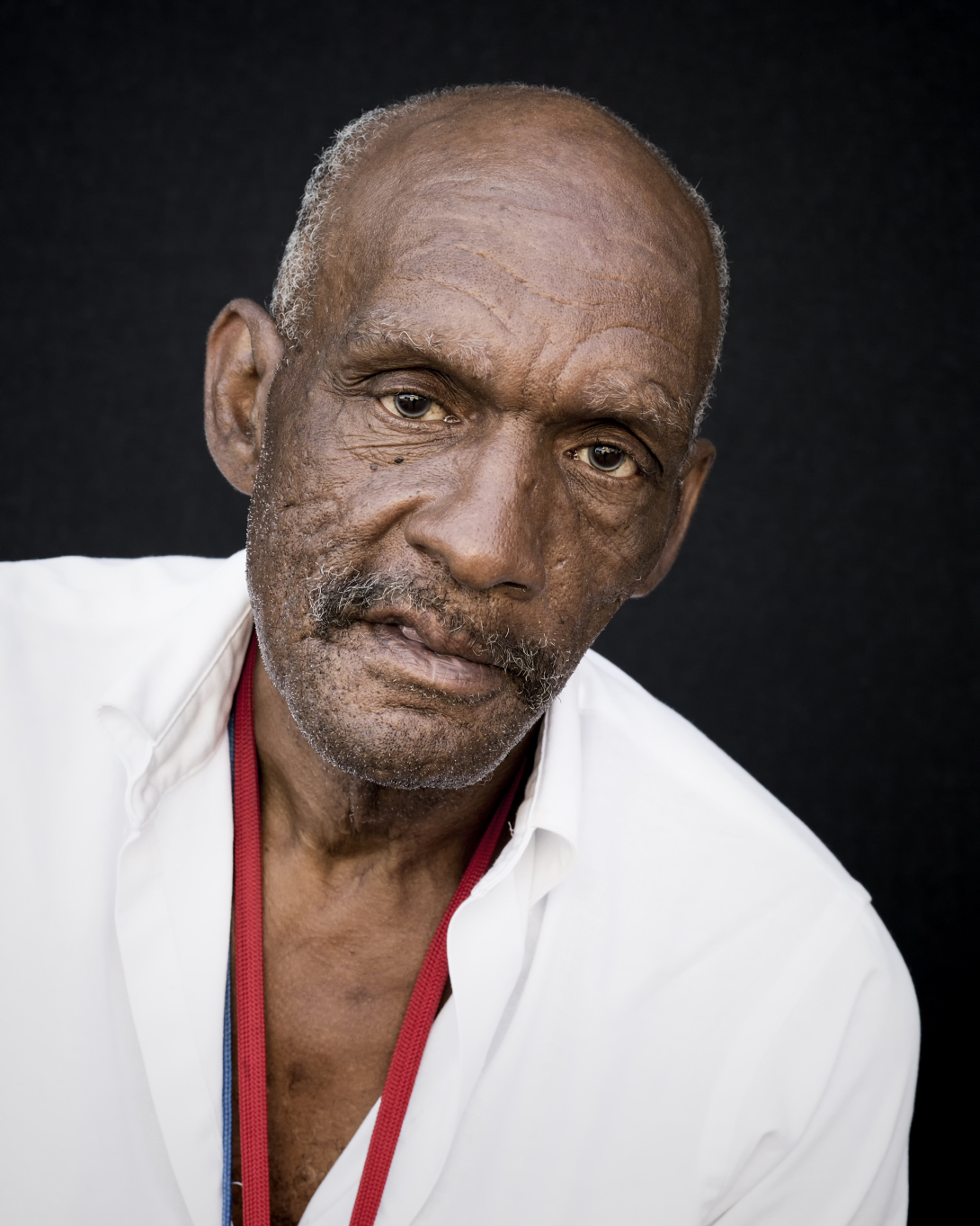 Imagem de homem negro idoso, com camisa branca.